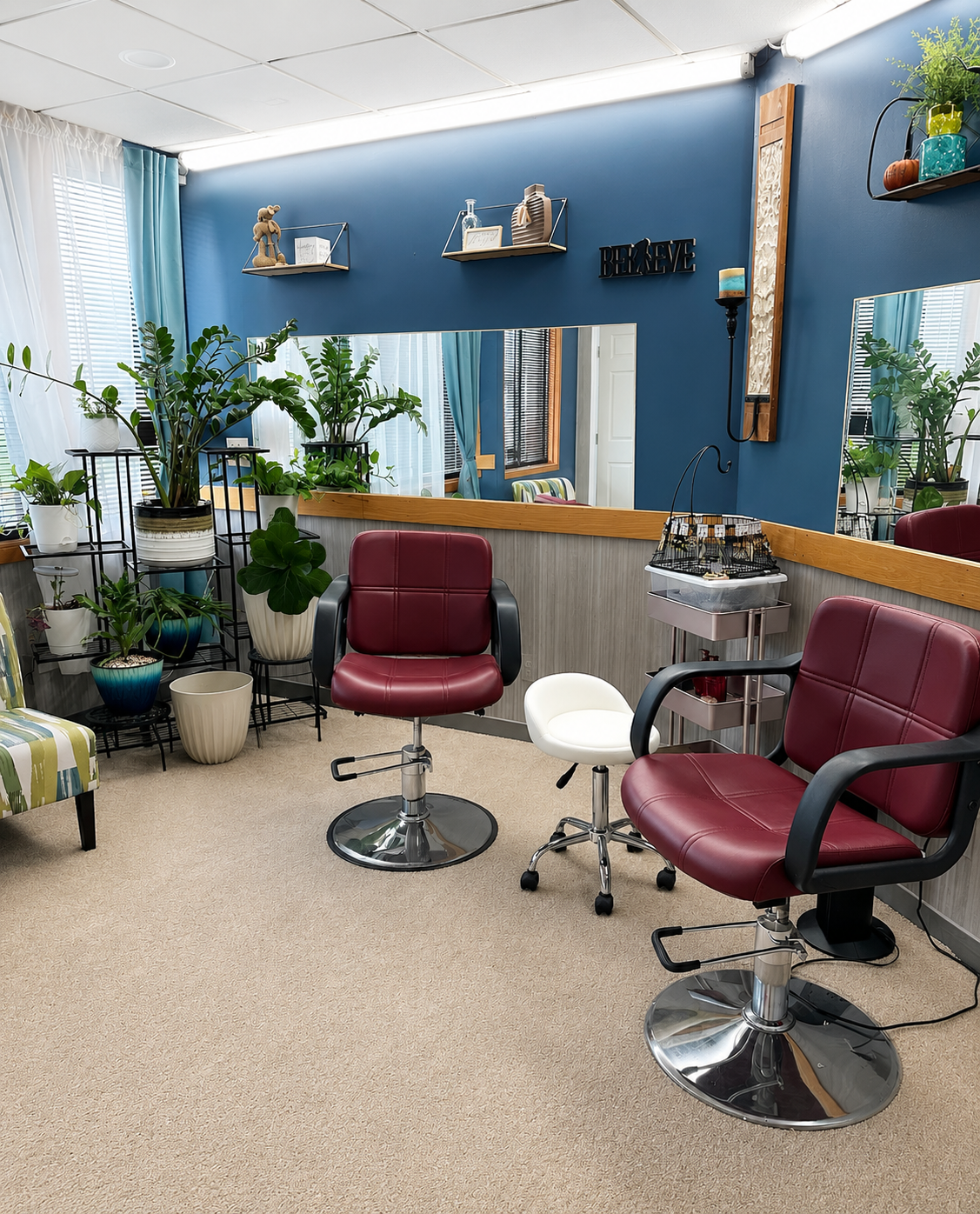 Nia's Crown Salon interior with burgundy styling chairs, deep blue accent wall, and lush plants